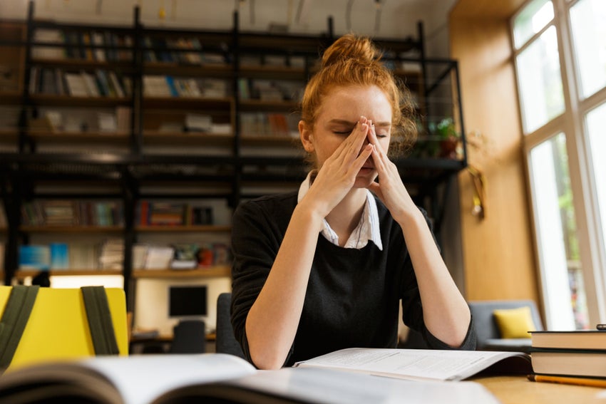 Exhausted,Red,Haired,Teenage,Girl,Studying,At,The,Table,In