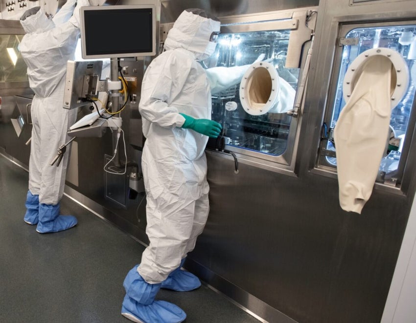 Novartis.two-associates-in-full-personal-protective-equipment-stand-at-the-production-line