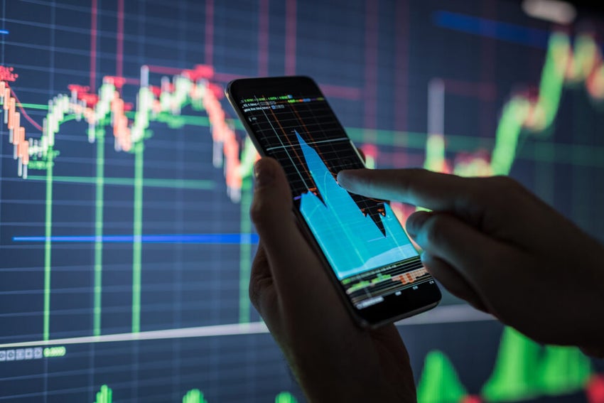 investor checking chart on mobile device with chart in background