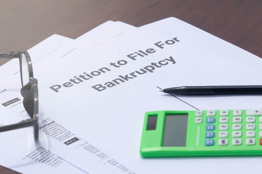 Petition for bankruptcy documents with pen, glasses and calculator
