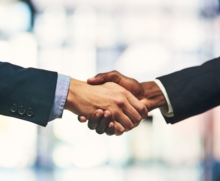 Two people shaking hands in business attire.