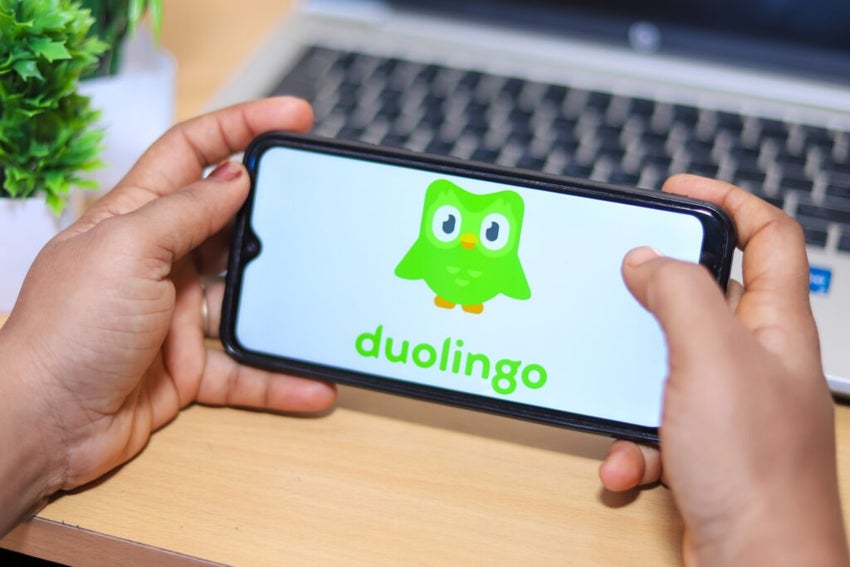 Hands holding phone with Duolingo app open.