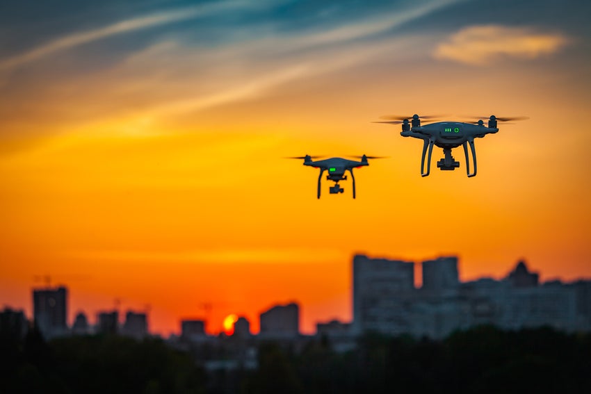 Two drones flying against vibrant sunset skyline