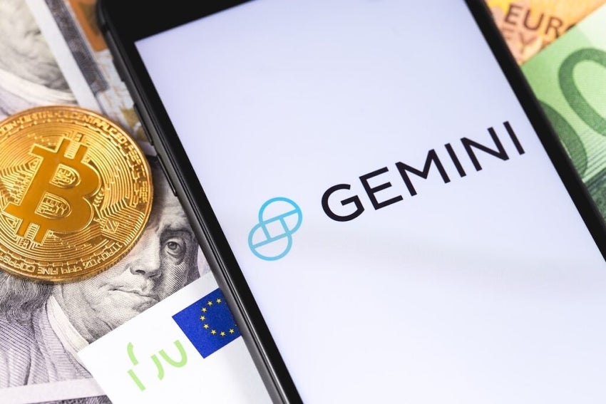 Gemini Exchange screen on a backdrop of bank notes and a Bitcoin