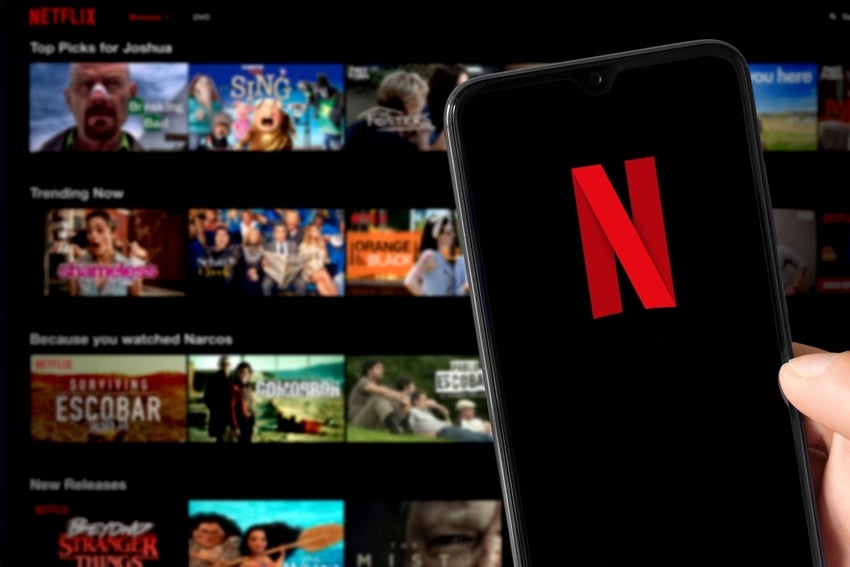 Smartphone with Netflix logo and Netflix catalog at background