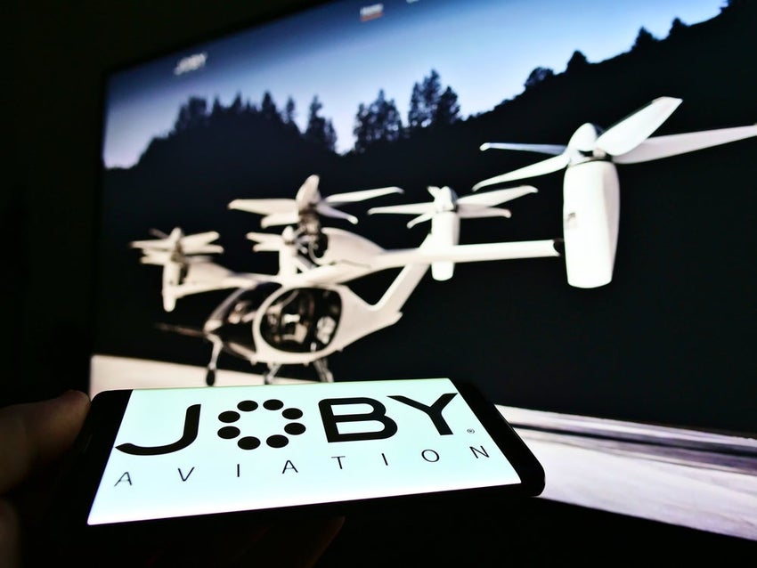 Joby logo in foreground with air taxis flying behind