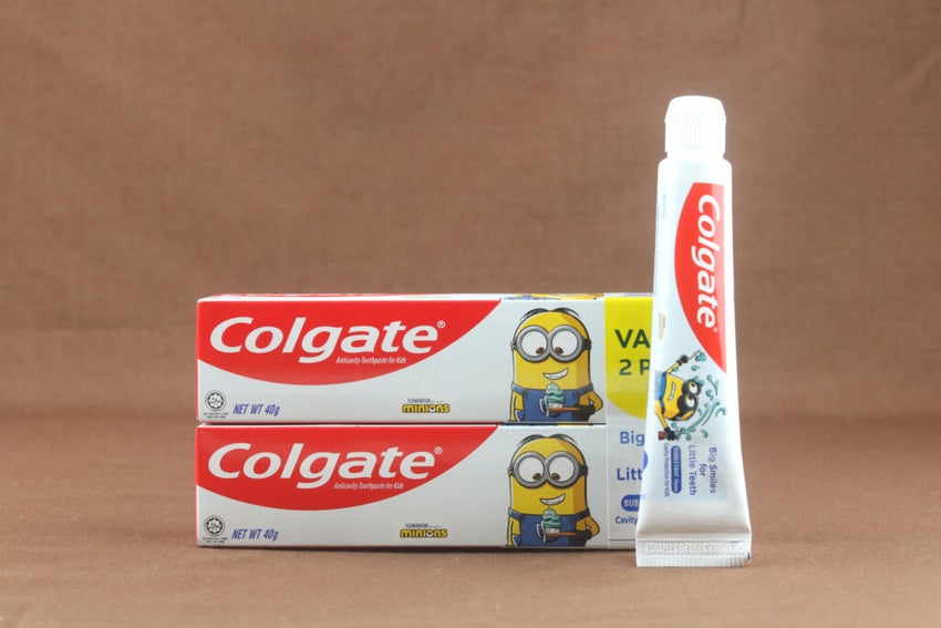 inion Colgate toothpaste for kids on brown backround. Brand of produced by Colgate-Palmolive. Selective focus.