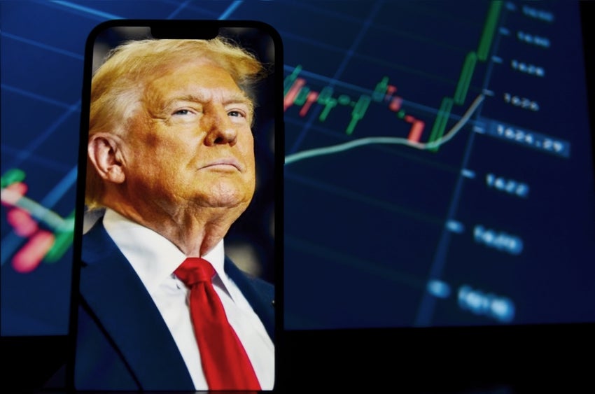 Donald Trump photo on smartphone with stock market chart background.