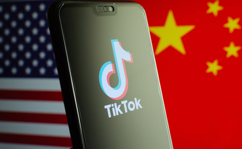 TikTok logo on smartphone screen and with US and China flags in background