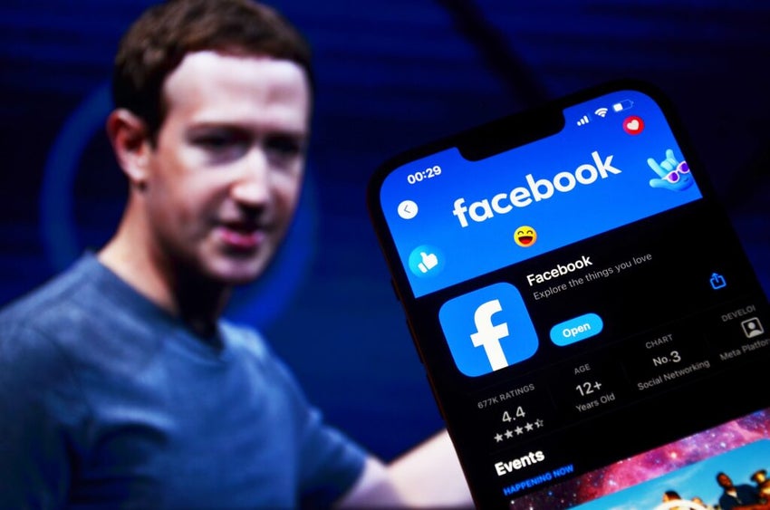 Facebook logo on screen with CEO Mark Zuckerberg