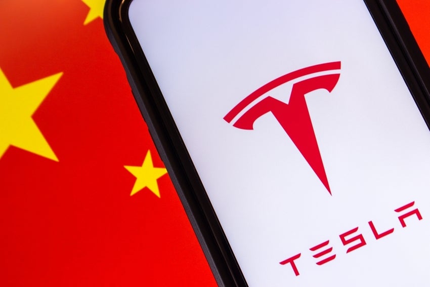 Tesla logo seen in smartphone on Chinese flag background.