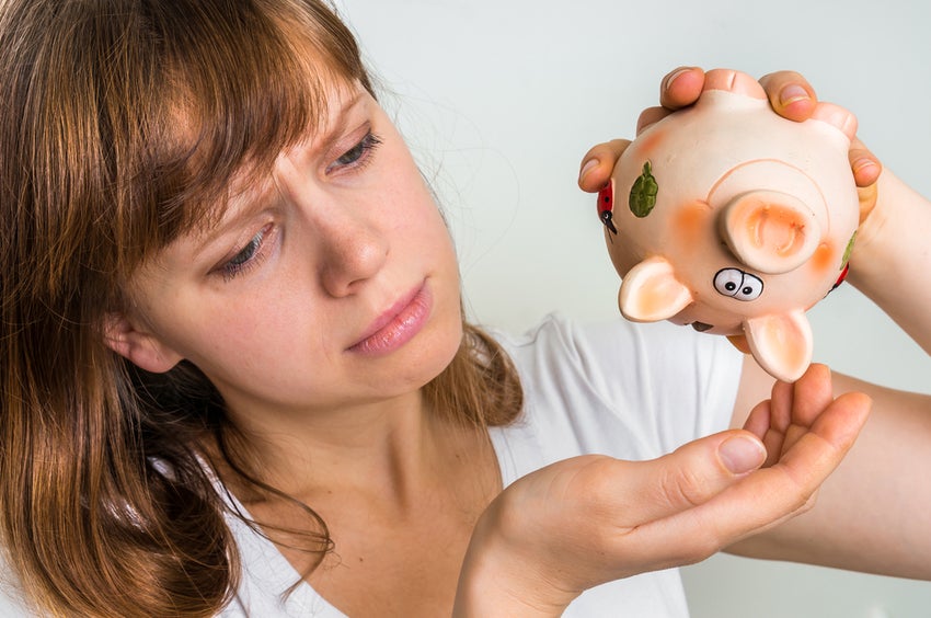 Person holding empty piggy bank, hoping for falling coins.