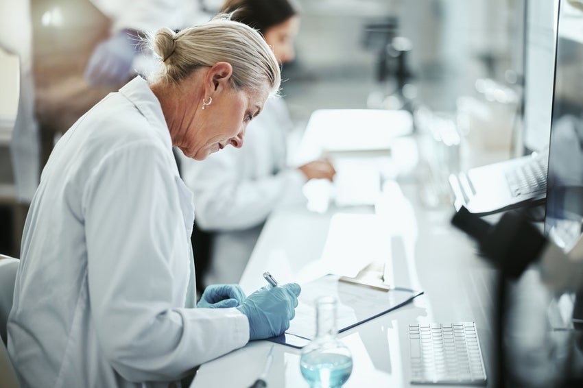 Scientist writing in laboratory for medical research.
