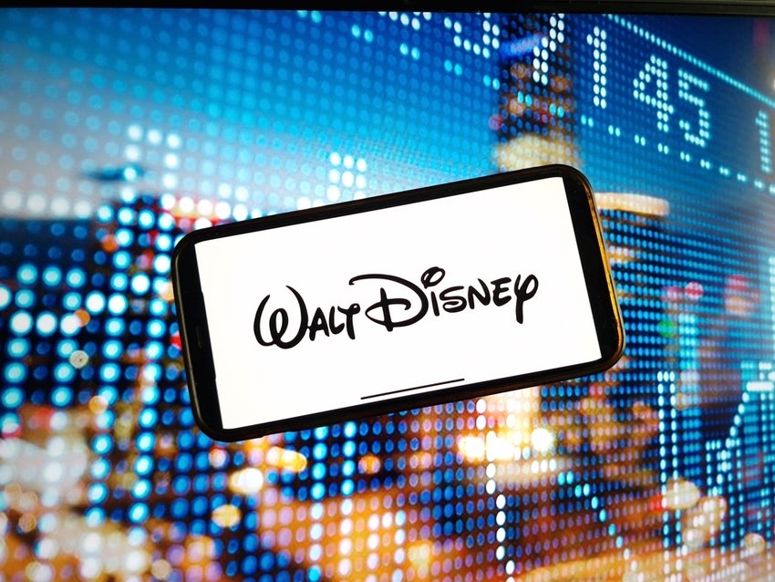 Walt Disney Pictures company logo displayed on mobile phone screen with stock market image in background