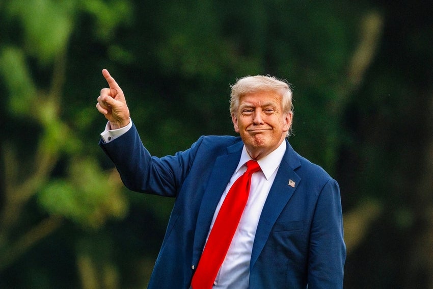 Trump pointing toward newly raised flag on the South Lawn