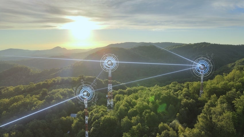 Communication towers with digital signals in wooded landscape.