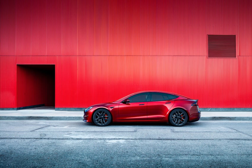 A red Tesla Model S parked in front of a red wall