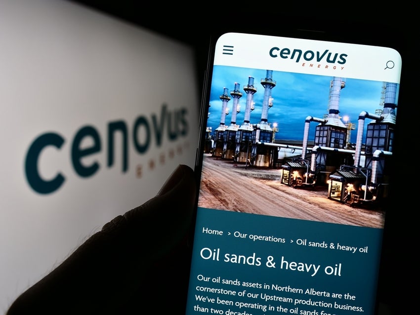 Person holding cellphone with webpage of Cenovus Energy Inc. on screen with logo