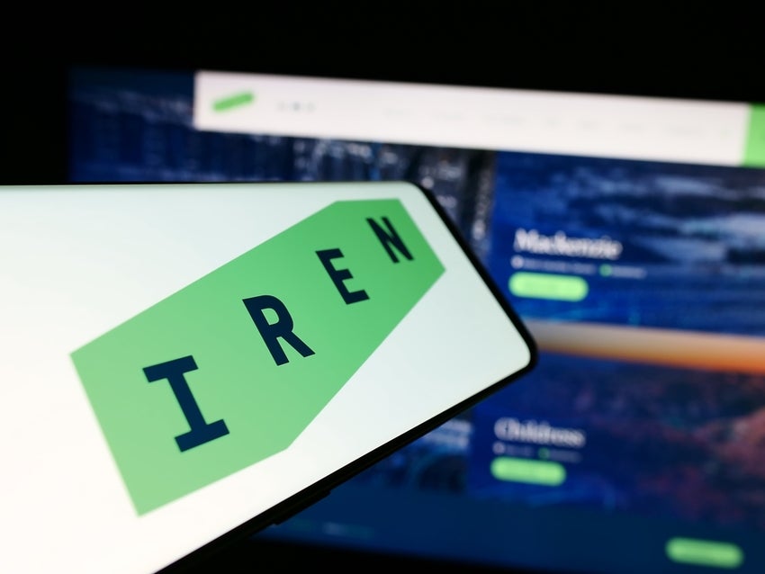Mobile phone with logo of IREN in front of website.