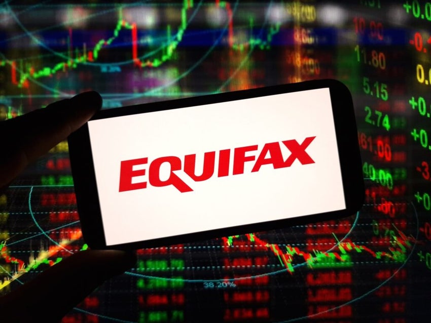 Equifax logo on smartphone against a financial chart on a screen