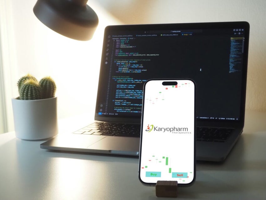 Karyopharm Therapeutics logo on smartphone screen in front of a laptop screen on a desk.