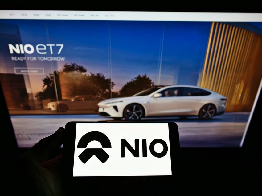 Nio logo smartphone in foreground, Nio car in background