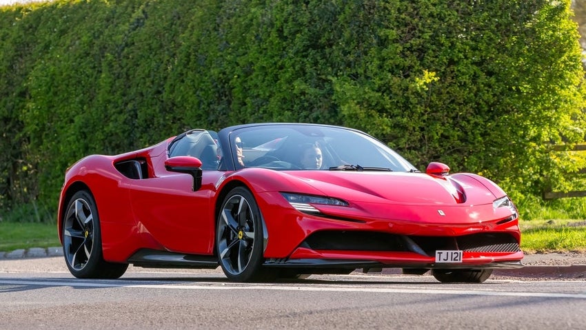 Red hybrid electric Ferrari SF90 Spider S-A classic car driving on a British road