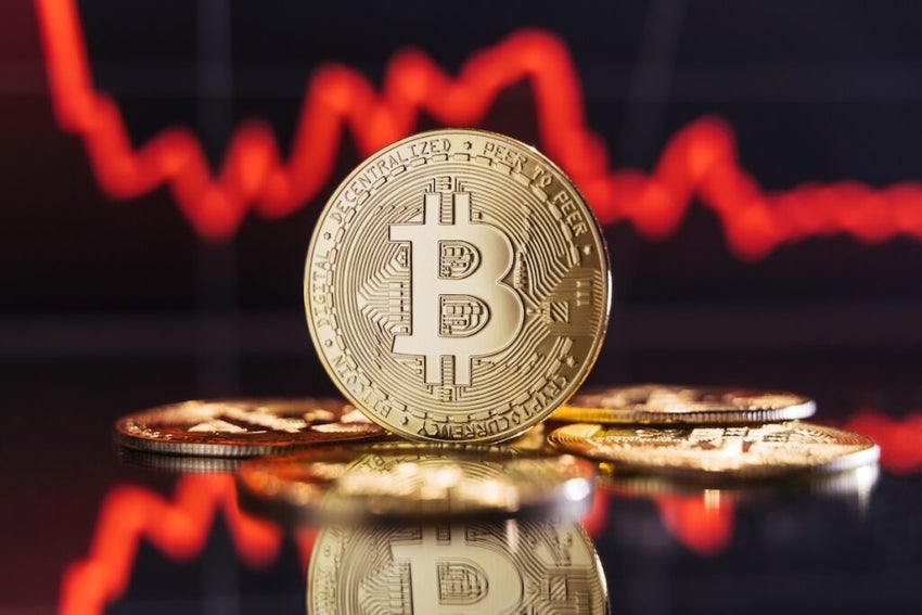 Image of golden bitcoin rising among piles of other crypto coins on digital background of chart with sole thick red line representing crash of crypto trading market