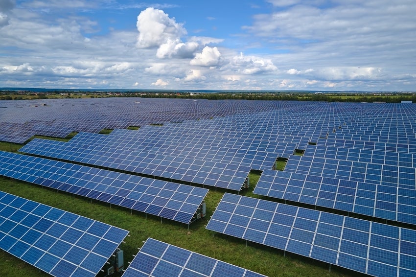 Aerial view of large sustainable electrical power plant with rows of solar panels.