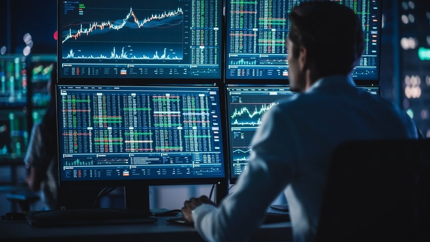 Day Trader Working on a Computers with Multi-Monitor Workstations with Real-Time Stocks.