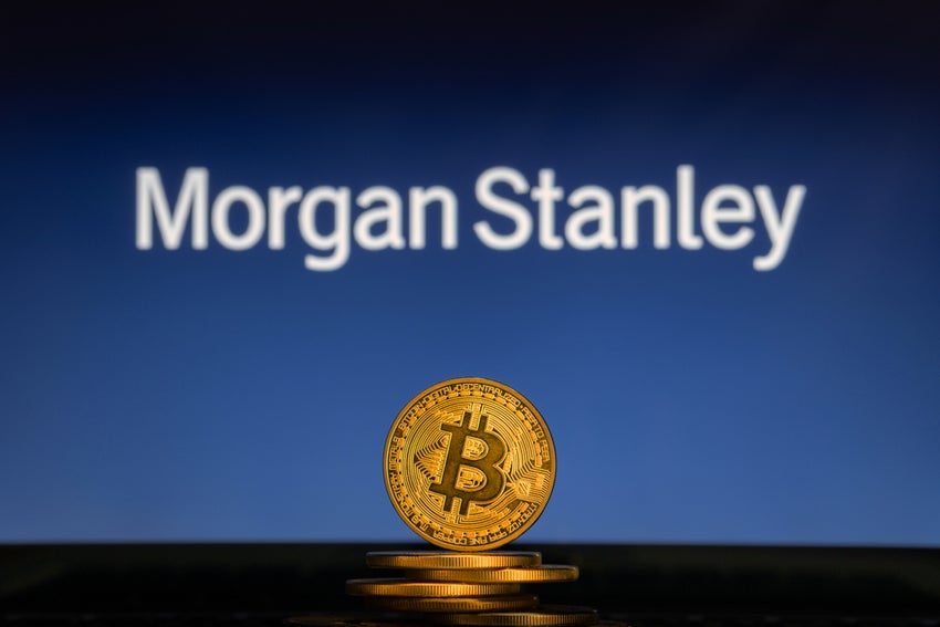 Bitcoin on a stack of coins with Morgan Stanley logo on a laptop screen.