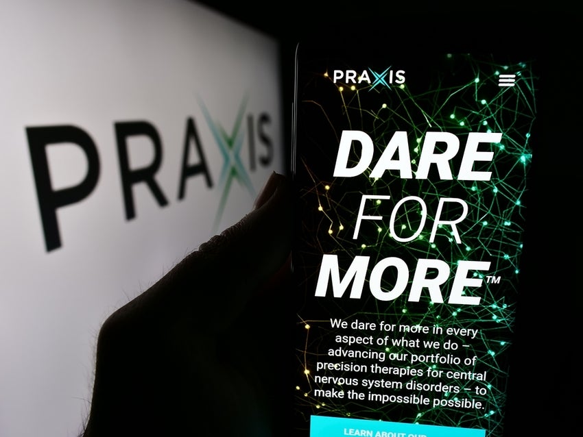 Person holding cellphone with website of US biopharma company Praxis Precision Medicines Inc. in front of logo.