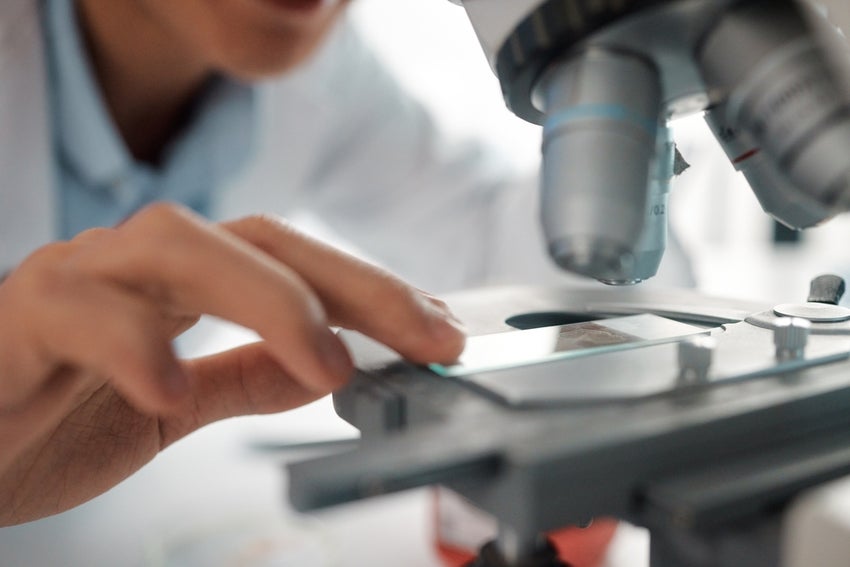 Research scientist in lab looking at microscope