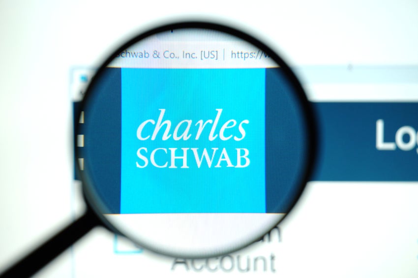 A magnifying glass focuses on the Charles Schwab logo on a computer screen.