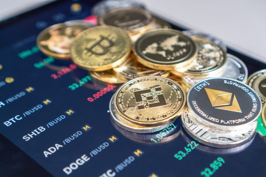 Cryptocurrency coins displayed on trading screen background.