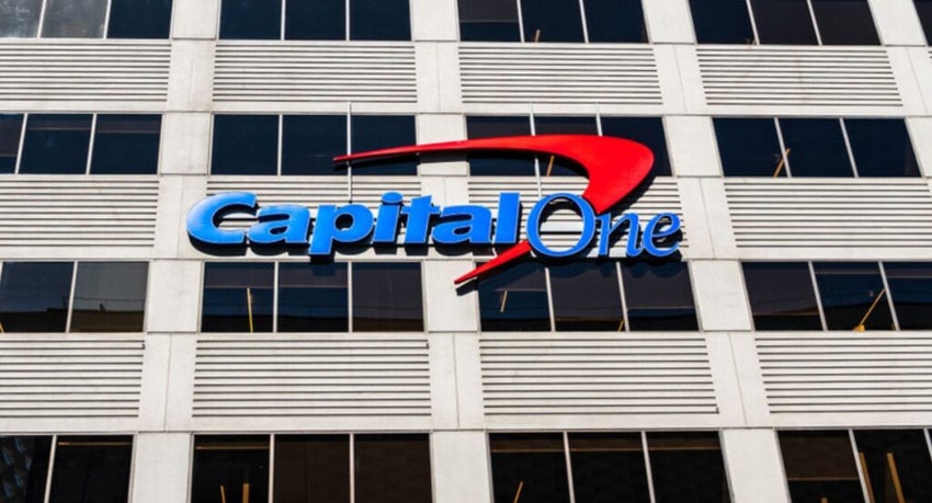 The blue and red Capital One logo is mounted on the glass facade of a modern, multi-story office building.