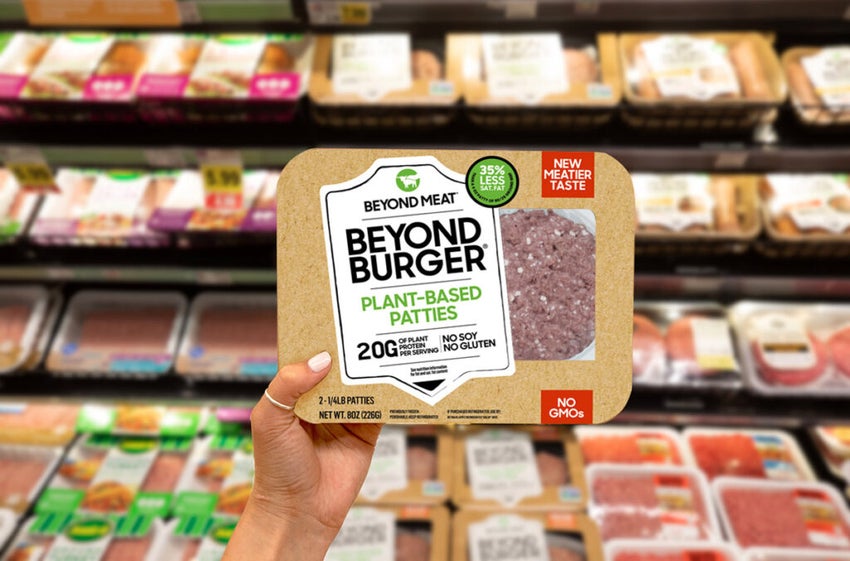 Beyond Meat Burger package held up in front of the meat aisle of a grocery store.