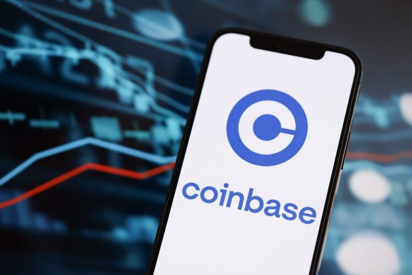 Coinbase logo on iphone screen agains a finanacial chart