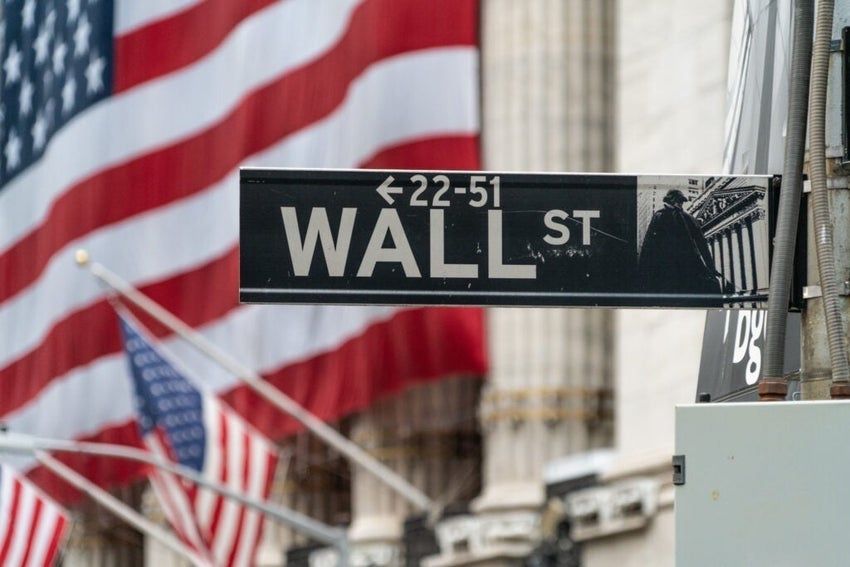 Close-Up Of Wall Street Sign With Iconic New York Skyscraper Backdrop