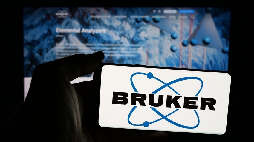 Person holding mobile phone with logo of American instruments company Bruker Corporation on screen in front of web page.