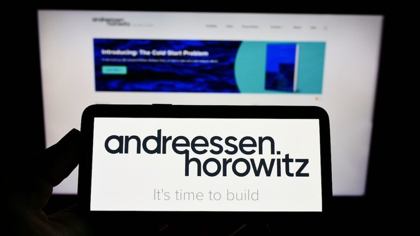 Person holding cellphone with logo of US venture capital firm Andreessen Horowitz (a16z) on screen in front of webpage. Focus on phone display. Unmodified photo.
