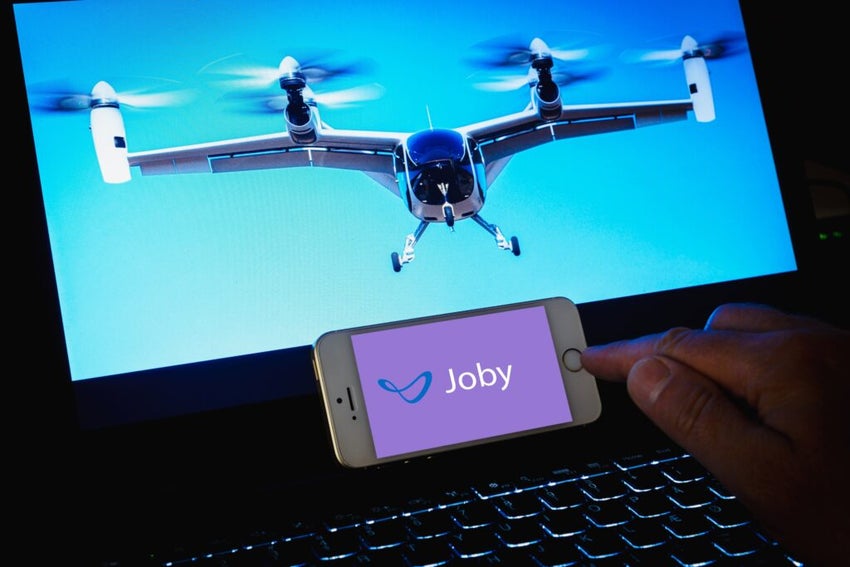 Joby Aviation logo.Person holding smartphone. Joby Aviation is a USA company creating an electric aircraft for air taxi services.Telsiai,Lithuania.08-09-2023.