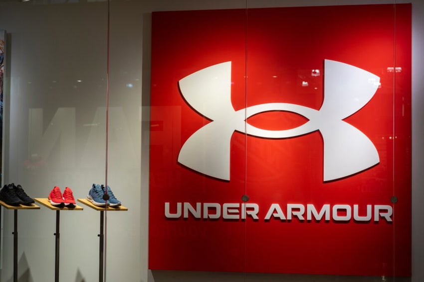 The Under Armour logo and shoes are pictured. Under Armour is a manufacturer of shoes, clothing, and athletic apparel.