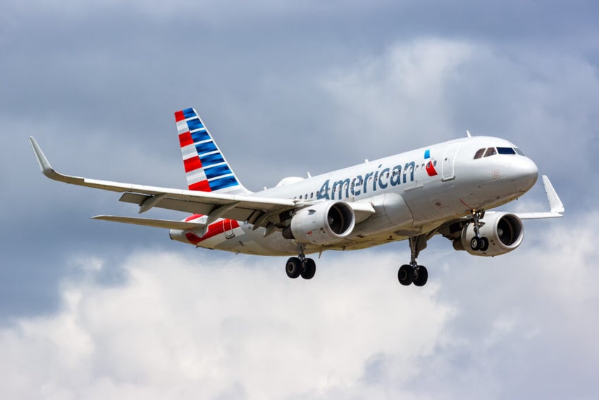 Airplane with American Airlines livery flying in cloudy sky.