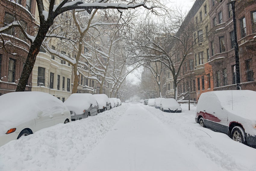 Snow covered street and Brownstone buildings during snowstorm in NYC