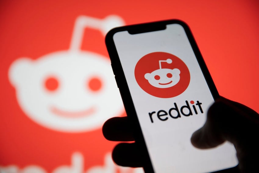 Reddit logo on smartphone against a logo backdrop