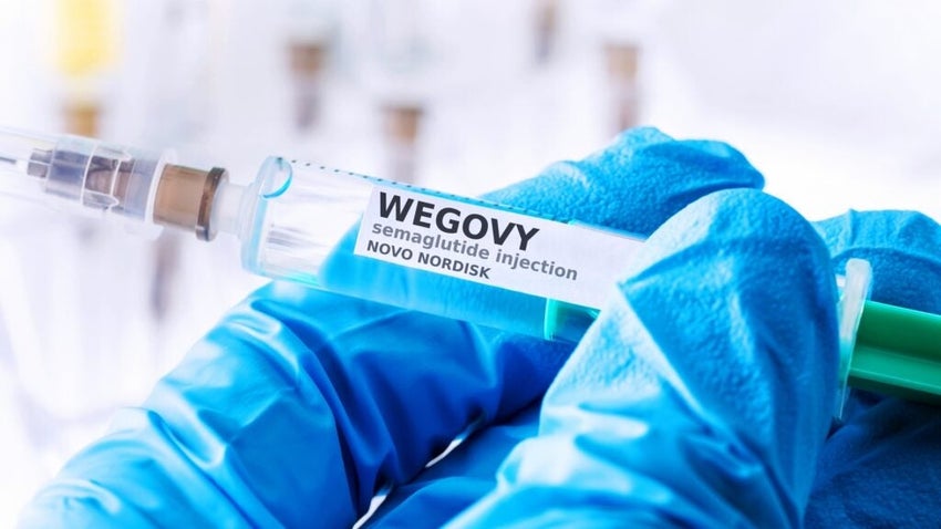 Gloved hand holding Wegovy semaglutide injection syringe