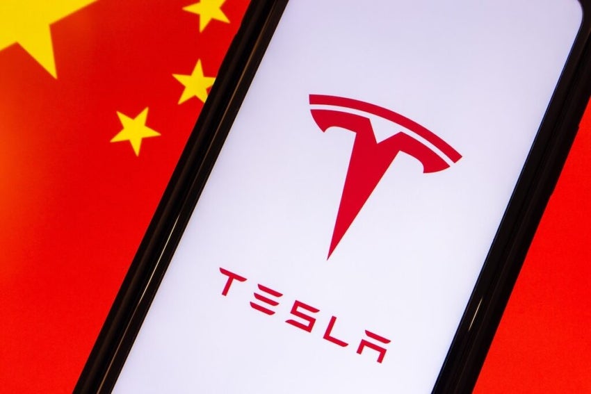 The logo of US multinational automotive, AI, and sustainable energy company Tesla seen in smartphone, on Chinese flag background.