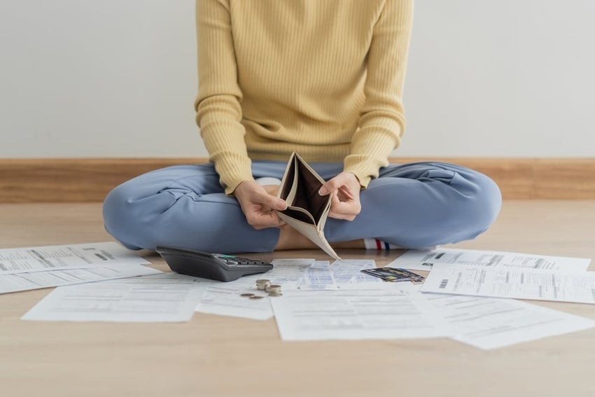 person sitting on the floor opening up an empty wallet