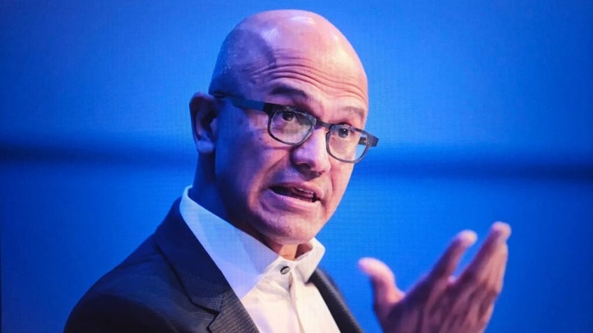 Satya nadella, ceo of microsoft, speaking at an event with a blue background and wearing glasses and a dark suit jacket, New York City, October 06, 2025